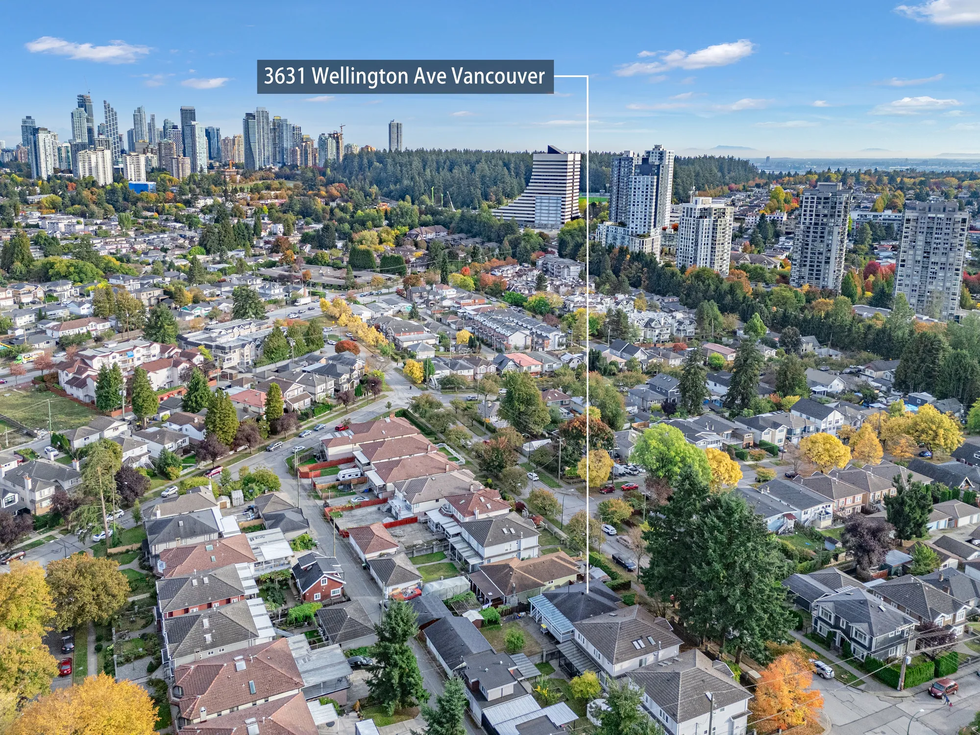 A high view over the neighbourhood toward the towers of Metrotown and a stretch of forest, the house marked with a label reading 3631 Wellington Ave Vancouver