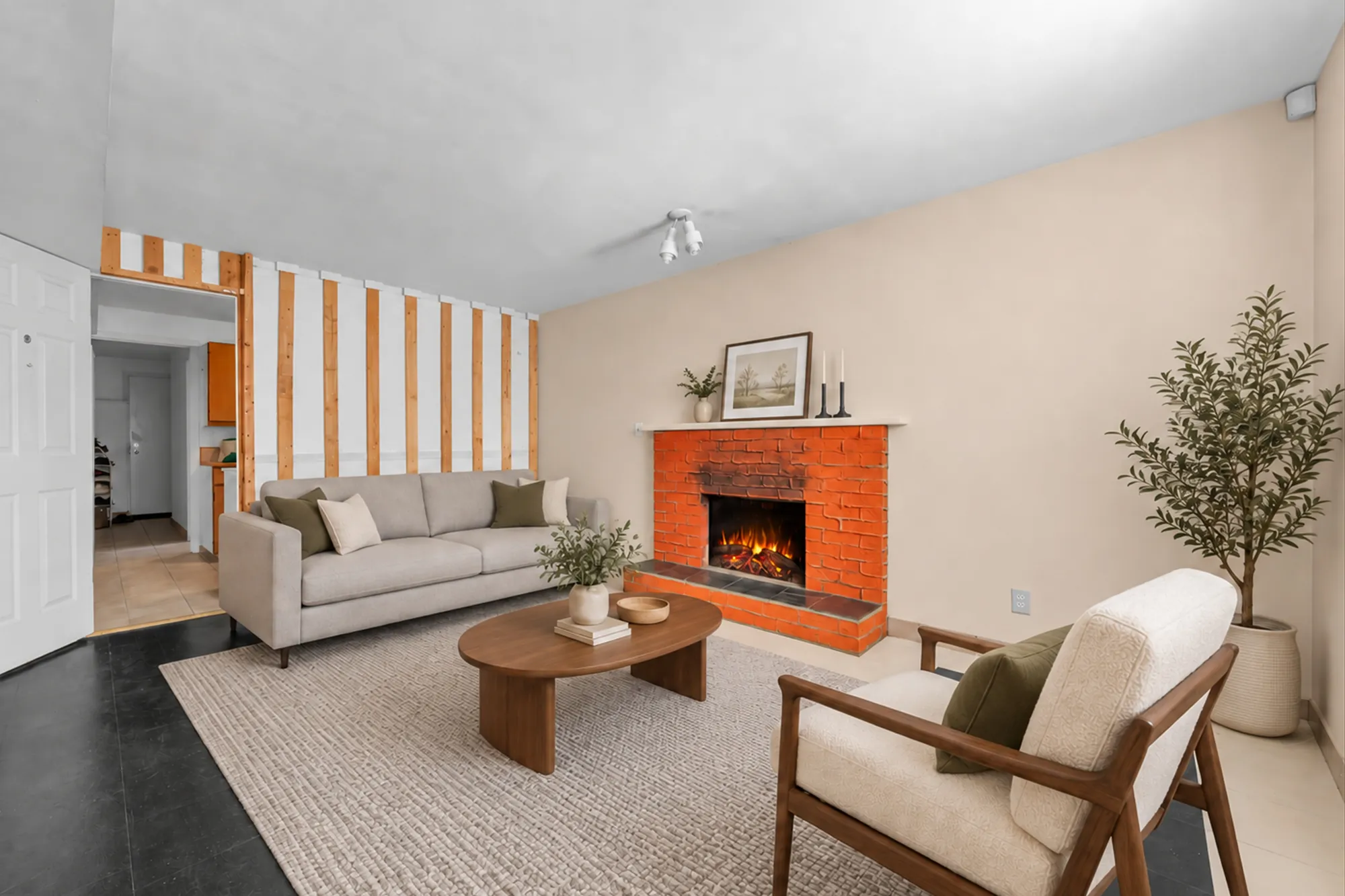 The same frame virtually staged: a beige sofa, an armchair, an oval coffee table on a rug, an olive tree, a print on the mantel