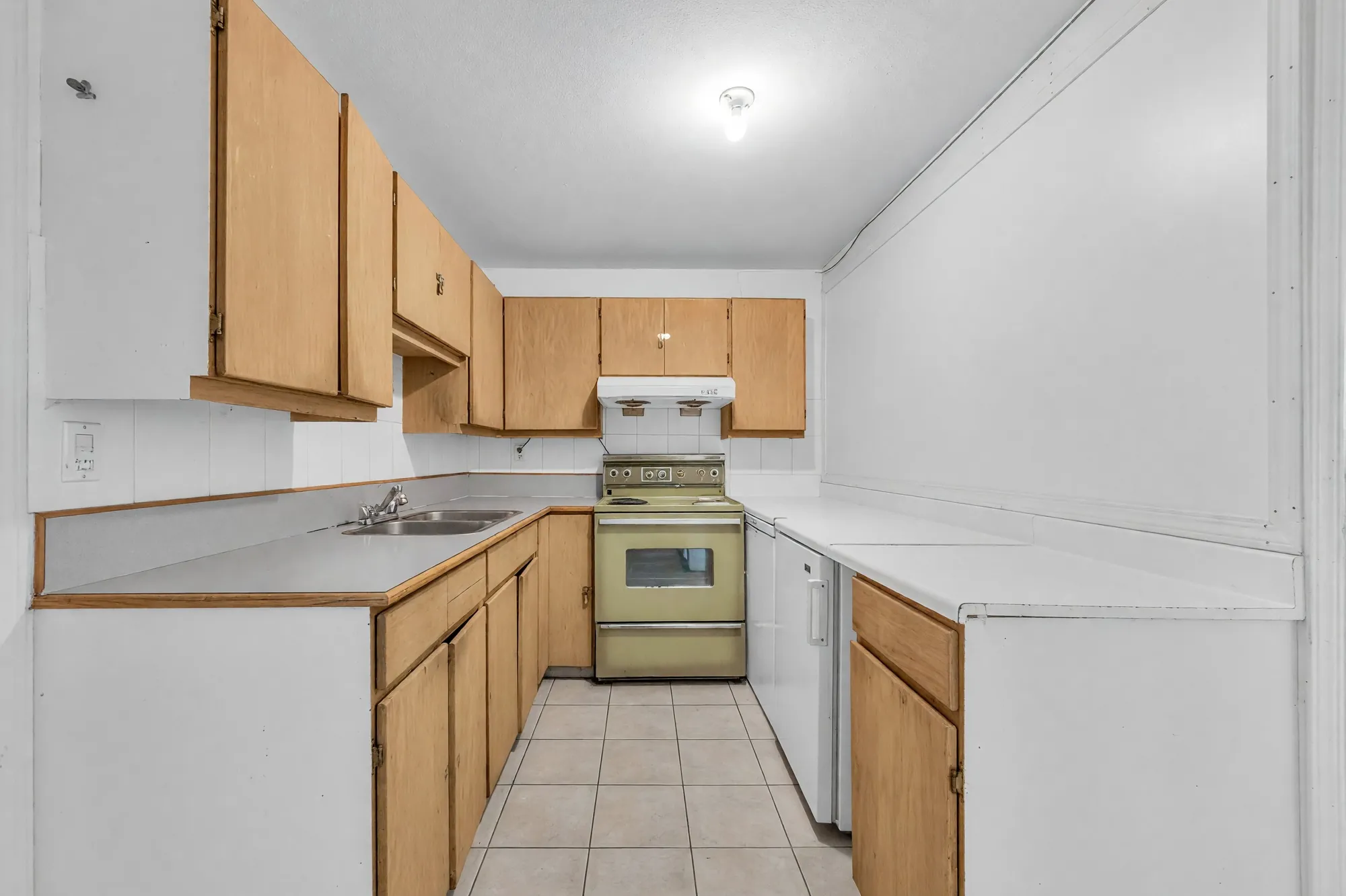 The lower kitchen end to end: wood cabinets on both sides, the range at the far end