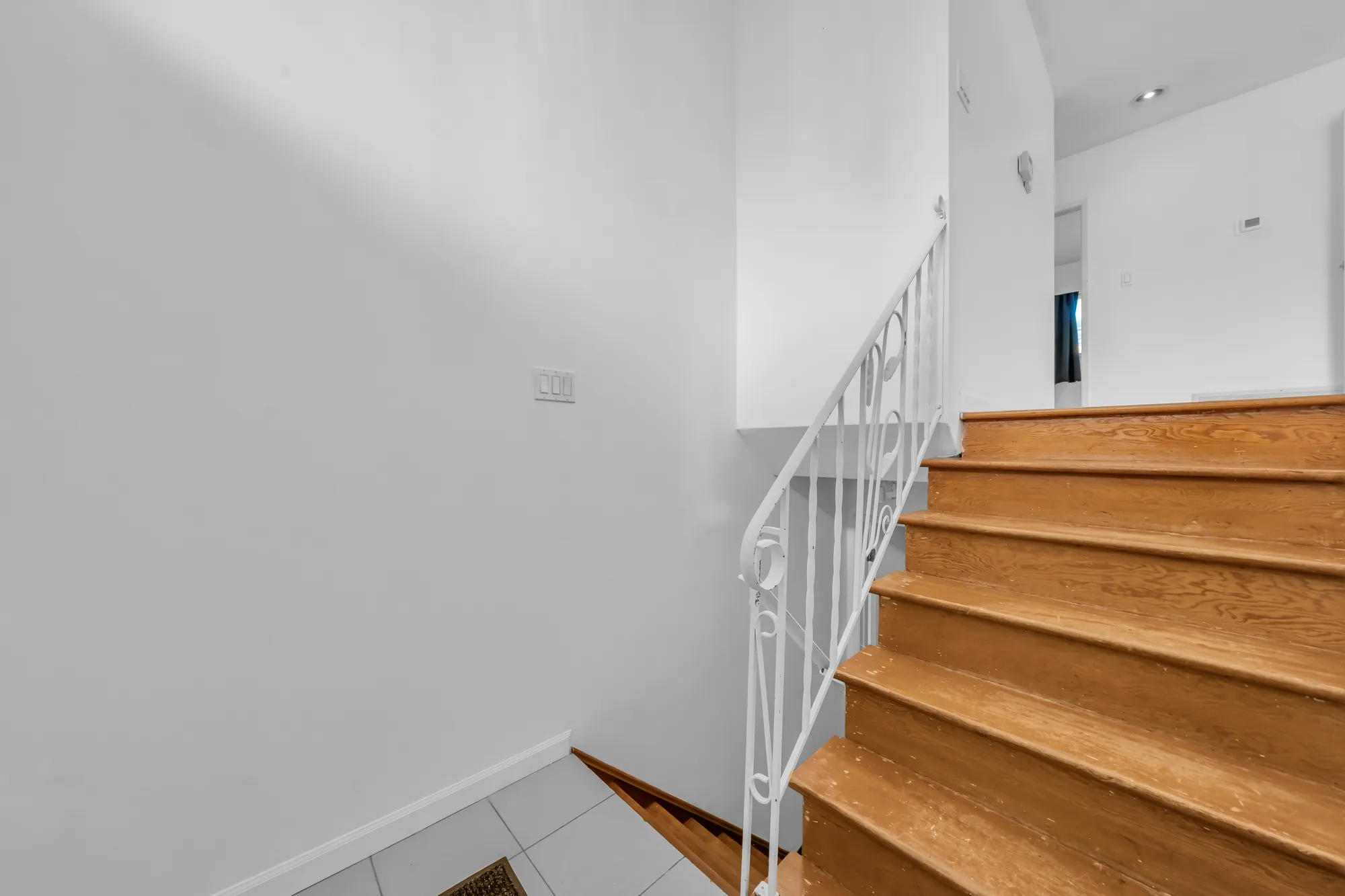 The stair up from the lower foyer: oak treads, a white wrought-iron railing